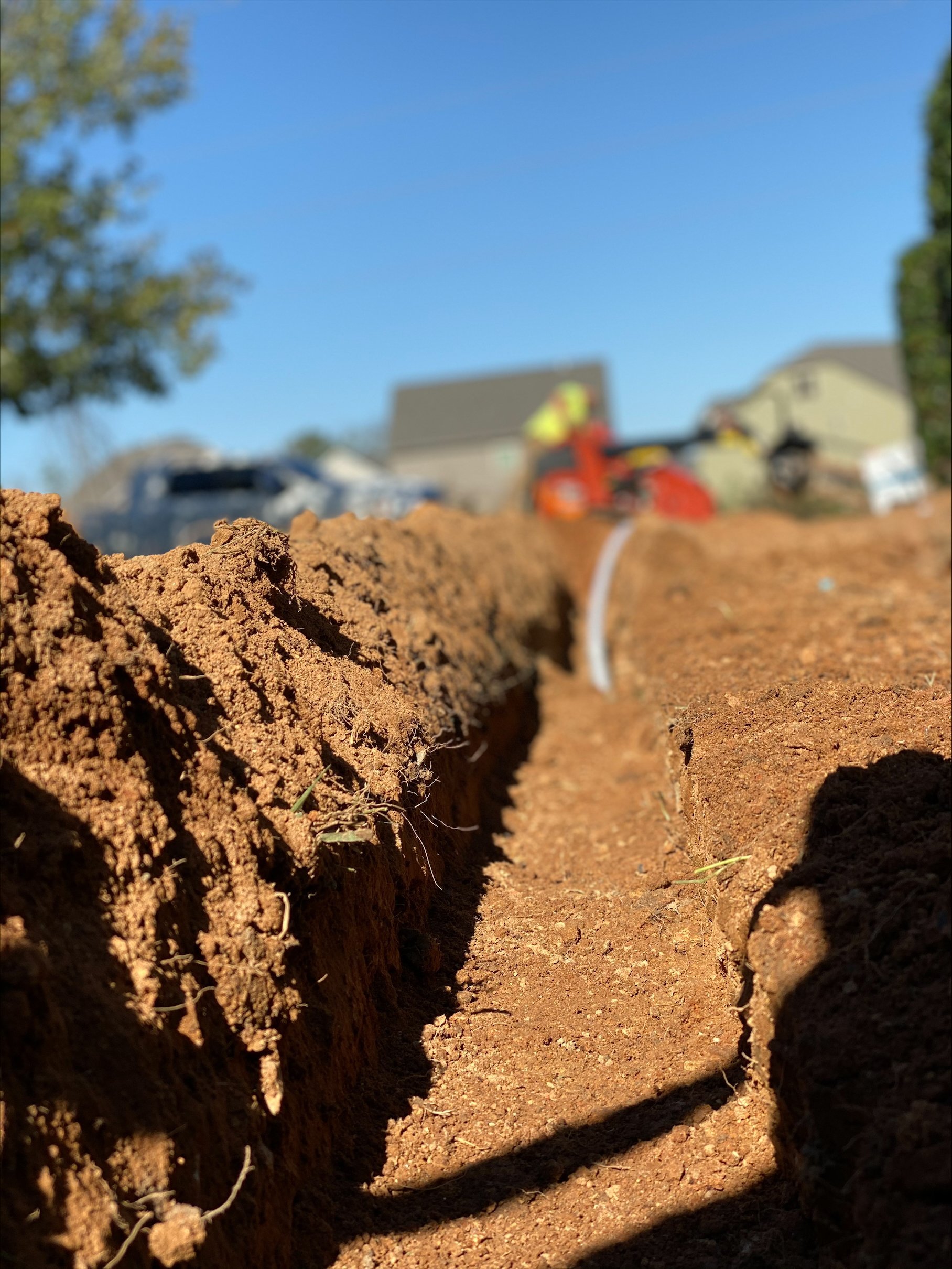 Close-up of freshly turned brown soil with excavation equipment and machinery blurred in the background on a construction site