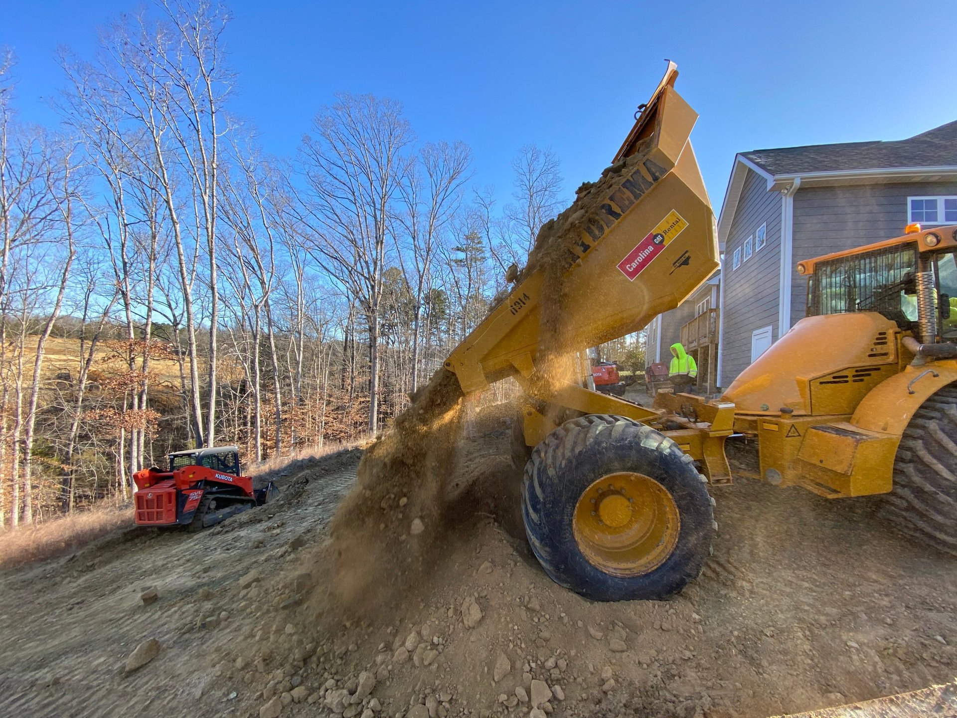 Yellow wheel loader dumping dirt and gravel at a construction site