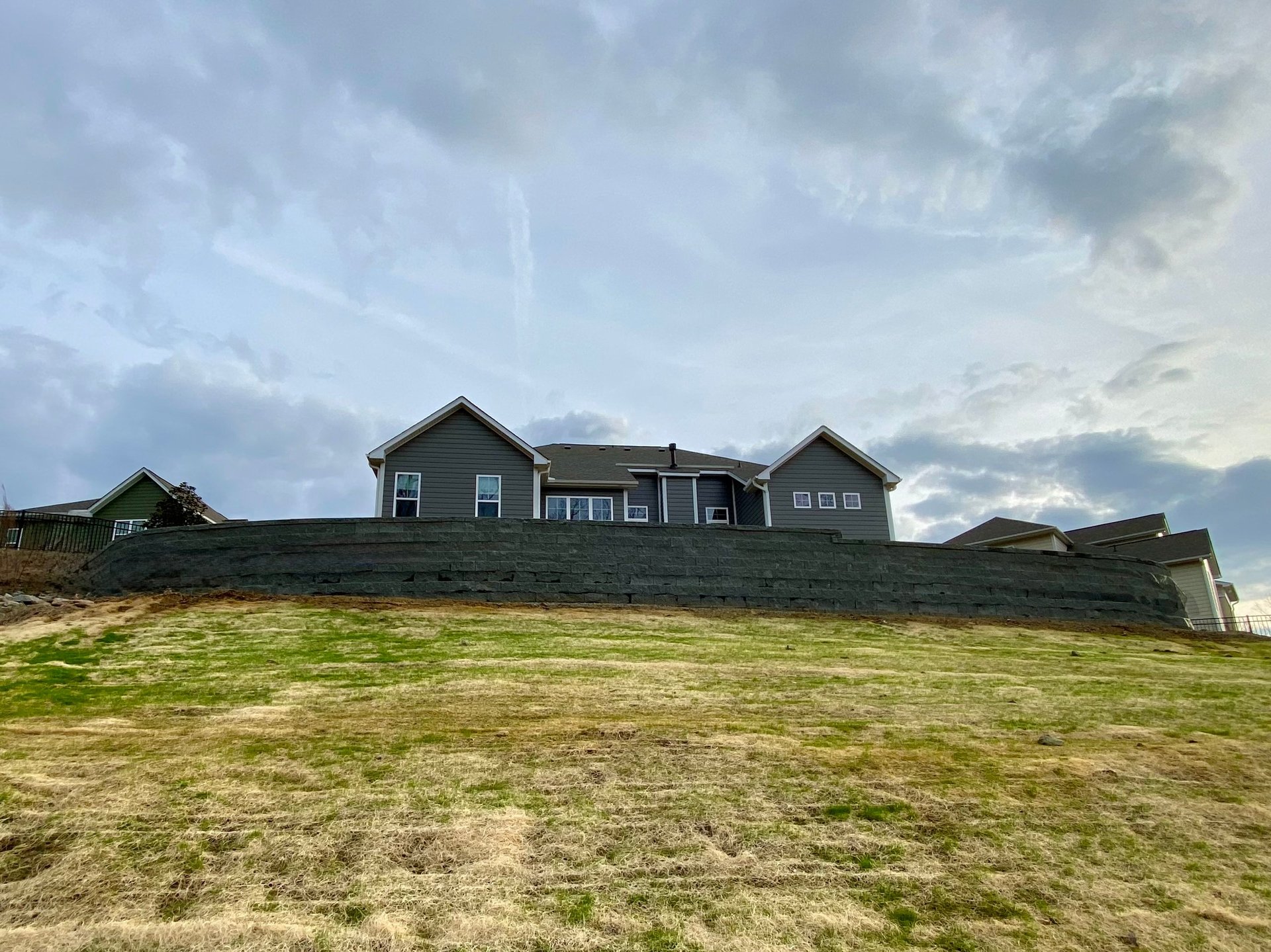 Large gray farmhouse on a grassy hill under a cloudy sky